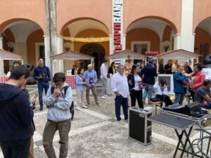 Cortile storico allestito per fiera enogastronomica con chioschi in legno e postazione audio regia con casse.