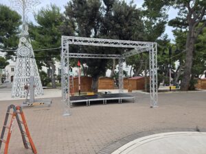 Vista laterale di una struttura americana a traliccio in alluminio con palco modulare montata in una piazza pubblica per eventi.