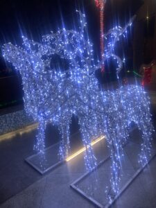 Primo piano di due grandi renne luminose 3D accese di notte, posizionate su basi metalliche autoportanti per decorazioni festive esterne.