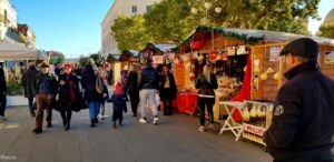 Fila di chioschi in legno e bancarelle a noleggio per mercatini ed eventi di piazza affollati.