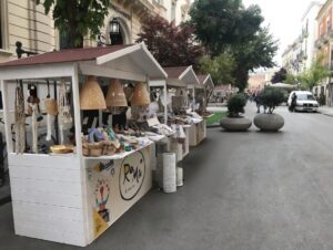 Chioschi in legno bianco a noleggio per l'allestimento di mercatini dell'artigianato in aree pedonali.