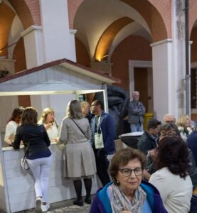 Chiosco espositivo in legno bianco a noleggio con visitatori all'interno di un cortile storico.