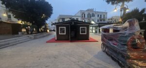 Grande chiosco in legno scuro a noleggio allestito su una passatoia rossa in una piazza esterna.