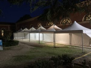 Fila di gazebo a pagoda bianchi illuminati di notte per un evento in giardino o ricevimento serale.