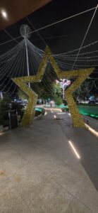 Grande stella di Natale luminosa tridimensionale con apertura per passaggio pedonale installata in una via pubblica di notte.