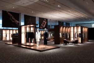 Showroom espositivo di lusso con manichini che indossano abiti eleganti e pareti attrezzate con scaffali illuminati.